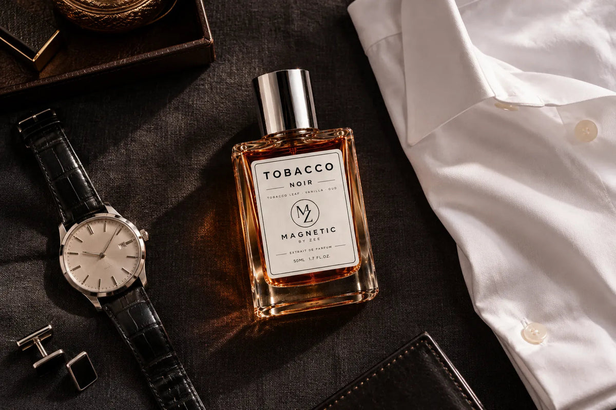TOBACCO NOIR bottle laid out with a white dress shirt, a leather strap watch, cufflinks and a wallet on dark fabric