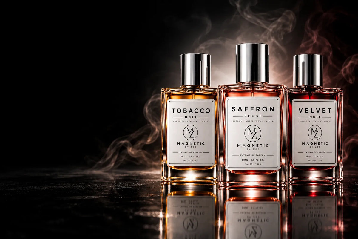 The MAGNETIC BY ZEE collection: TOBACCO NOIR, SAFFRON ROUGE and VELVET NUIT bottles on a black reflective surface with drifting smoke